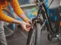 Osoba w żółtym swetrze dokonuje wymiany klocków hamulcowych w rowerze, dbając o bezpieczeństwo jazdy.