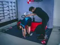 Pomiar rozstawu kości kulszowych w bike lab. Kobieta pochyla się, mężczyzna pomaga w ustaleniu punktów.