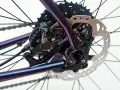 Błyszcząca, fioletowa sztywna oś w rowerze z tarczą hamulcową Shimano i kasetą.