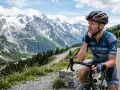 Kolarz w kasku i stroju Bike & Beyond odpoczywa na trasie w Dolinie Chochołowskiej, podziwiając majestatyczne, ośnieżone szczyty.