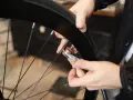 Ręce przy kole rowerowym, klucz do wentyla. Dowiedz się, jak wymienić dętkę w rowerze krok po kroku.
