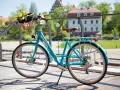 Turkusowy rower z koszykiem pełnym żółtych tulipanów. Dowiedz się, jak zamontować koszyk do roweru, by cieszyć się wiosennymi przejażdżkami.