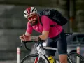 Rowerzysta w różowej koszulce i czarnych spodenkach, z plecakiem i kaskiem. Idealny strój, gdy zastanawiasz się, jak się ubrać na 7 stopni.