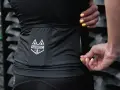 Dłonie z żółtym lakierem zamykają zamek w czarnej odzieży sportowej z logo MARDO. Idealne do prania odzieży sportowej.