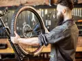 Mechanik z brodą sprawdza oponę gravel. Zastanawia się, ile mleka do opony gravel będzie potrzebne, by zapewnić optymalną jazdę.