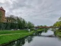 Oświęcim trasa: zamek, rzeka Soła i most na tle pochmurnego nieba.