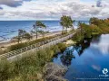 Dwie osoby na rowerach przemierzają malowniczą trasę EuroVelo wzdłuż morza i spokojnego jeziora.