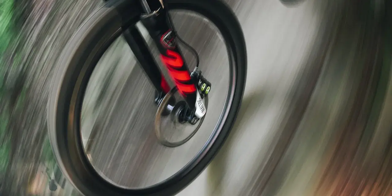 Przednie koło roweru enduro w ruchu, z widocznym amortyzatorem. Różne rodzaje amortyzatorów wpływają na jazdę.