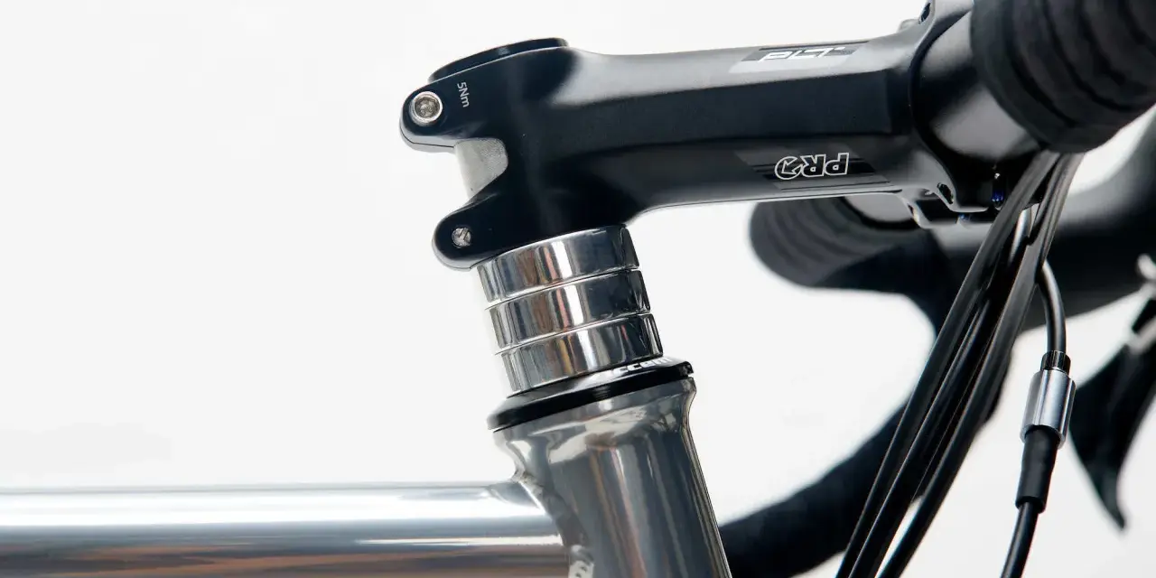 Czarne stery rowerowe PRO z aluminiowymi podkładkami, zamontowane na szarej ramie roweru szosowego.