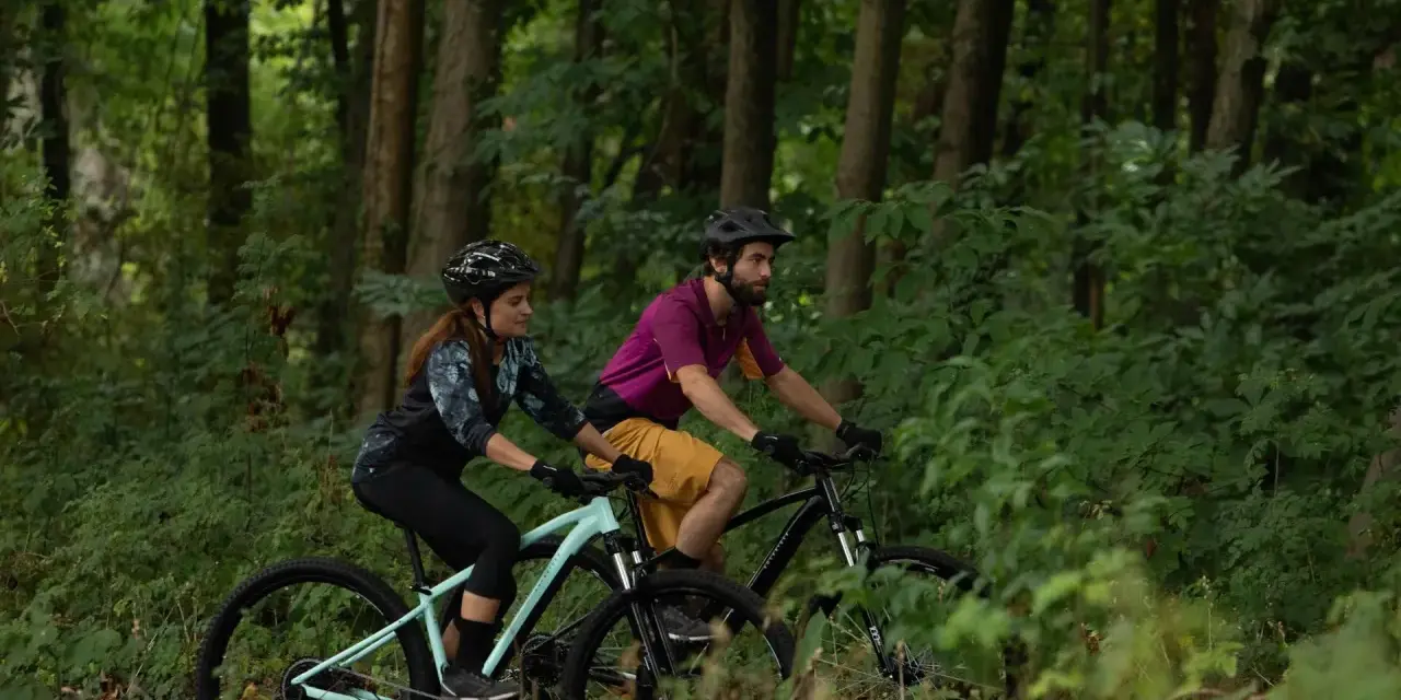 Para jadąca na rowerach MTB przez leśną ścieżkę. Czy to gravel czy mtb, jazda po lesie to czysta przyjemność.