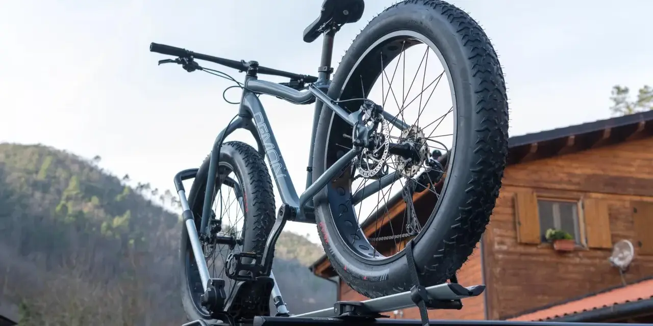 Gotowy montaż bagażnika rowerowego na dachu samochodu. Grube opony roweru fat bike są gotowe na przygodę.
