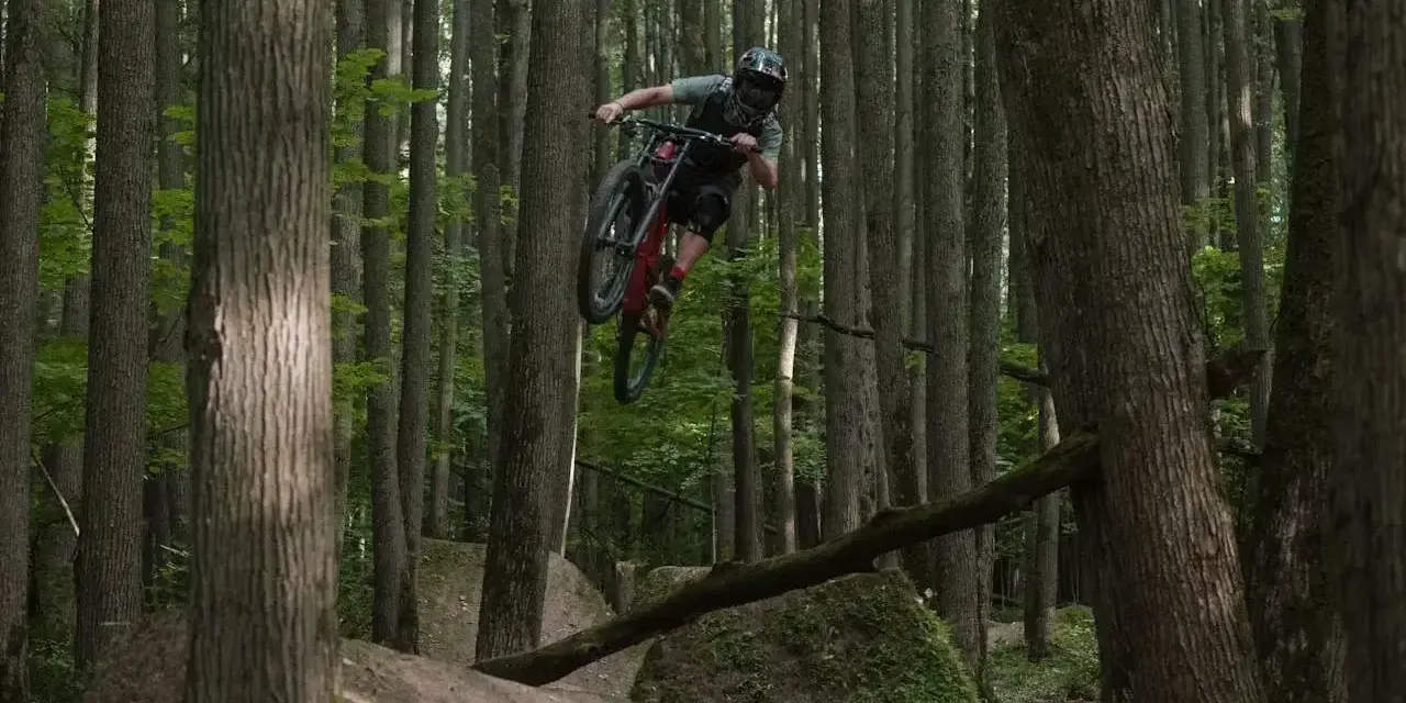 Kolarz MTB w powietrzu na leśnych trasach.
