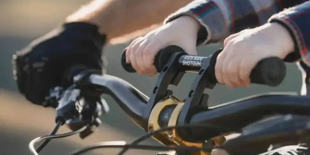 Dziecko trzyma kierownicę roweru, gotowe do jazdy. Wymiana manetek w rowerze to dobry pomysł na ulepszenie.