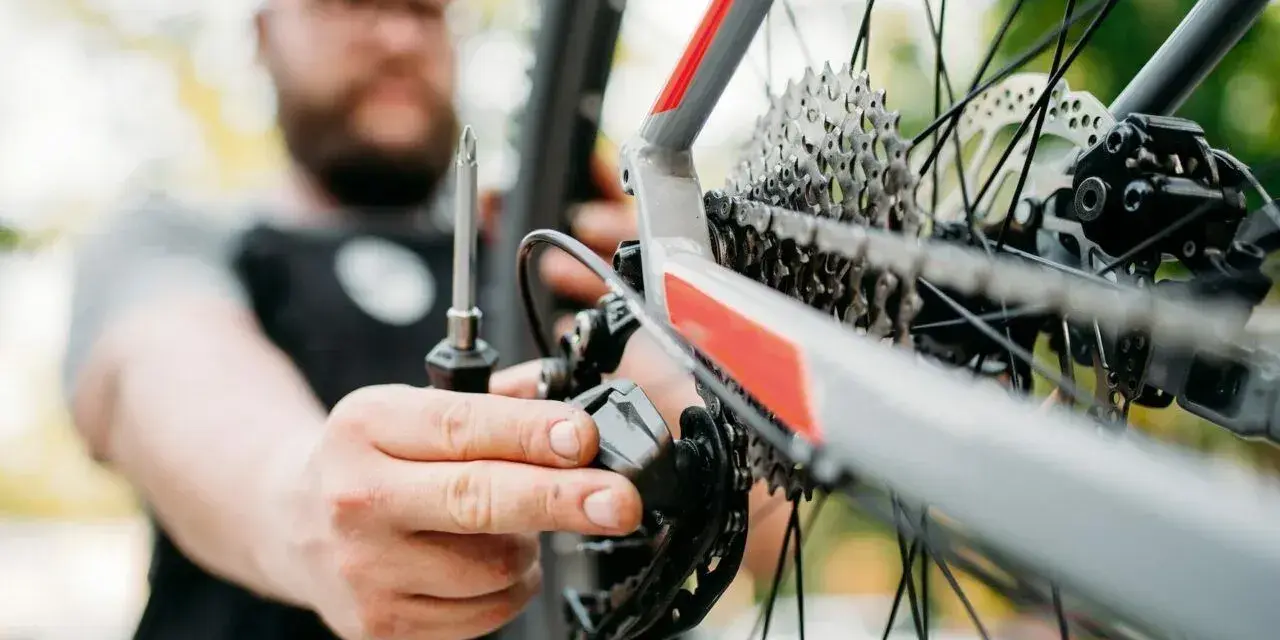 Mężczyzna z brodą dokręca śruby w rowerze, dbając o każdy szczegół.