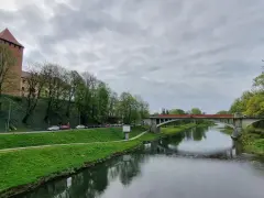 Oświęcim trasa: zamek, rzeka Soła i most na tle pochmurnego nieba.
