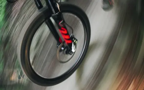 Przednie koło roweru enduro w ruchu, z widocznym amortyzatorem. Różne rodzaje amortyzatorów wpływają na jazdę.