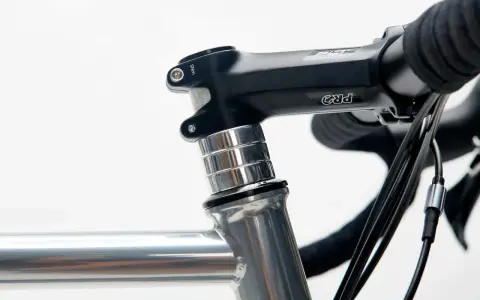 Czarne stery rowerowe PRO z aluminiowymi podkładkami, zamontowane na szarej ramie roweru szosowego.