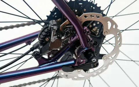 Błyszcząca, fioletowa sztywna oś w rowerze z tarczą hamulcową Shimano i kasetą.