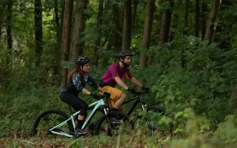 Para jadąca na rowerach MTB przez leśną ścieżkę. Czy to gravel czy mtb, jazda po lesie to czysta przyjemność.