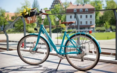 Turkusowy rower z koszykiem pełnym żółtych tulipanów. Dowiedz się, jak zamontować koszyk do roweru, by cieszyć się wiosennymi przejażdżkami.