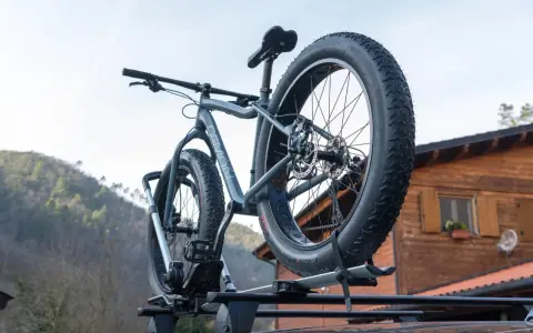 Gotowy montaż bagażnika rowerowego na dachu samochodu. Grube opony roweru fat bike są gotowe na przygodę.
