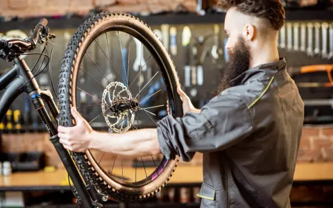 Mechanik z brodą sprawdza oponę gravel. Zastanawia się, ile mleka do opony gravel będzie potrzebne, by zapewnić optymalną jazdę.