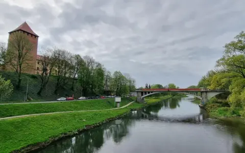 Oświęcim trasa: zamek, rzeka Soła i most na tle pochmurnego nieba.