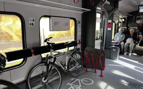 Wnętrze pociągu z miejscem na rowery. Widoczny stojak i uchwyty, jak powiesić rower w pociągu.