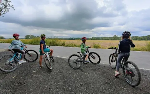 Dzieci na rowerach, idealny rower dla 8 latka to pewnie 20 cali. Czekają na przygodę na tle pól i chmur.