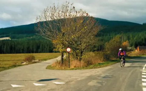 Rowerzysta mija znak drogowy, kierując się w stronę Babiej Góry.