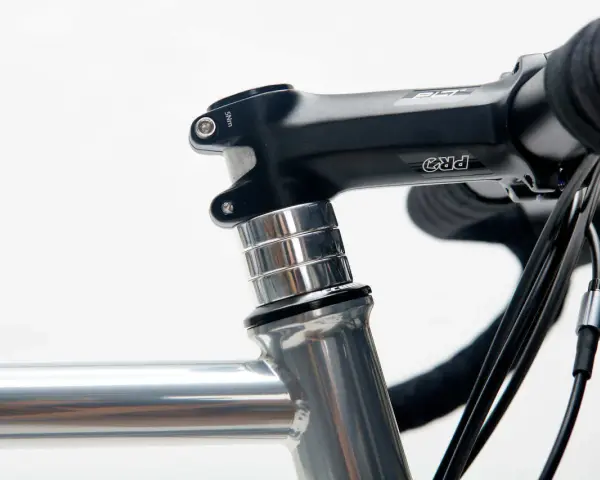 Czarne stery rowerowe PRO z aluminiowymi podkładkami, zamontowane na szarej ramie roweru szosowego.