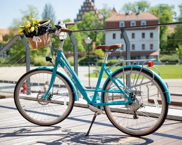 Turkusowy rower z koszykiem pełnym żółtych tulipanów. Dowiedz się, jak zamontować koszyk do roweru, by cieszyć się wiosennymi przejażdżkami.