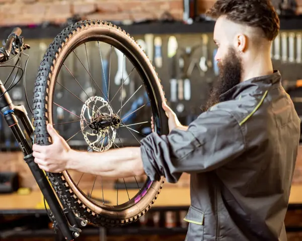 Mechanik z brodą sprawdza oponę gravel. Zastanawia się, ile mleka do opony gravel będzie potrzebne, by zapewnić optymalną jazdę.