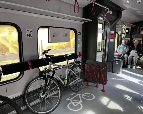 Wnętrze pociągu z miejscem na rowery. Widoczny stojak i uchwyty, jak powiesić rower w pociągu.