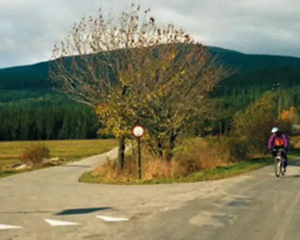 Rowerzysta mija znak drogowy, kierując się w stronę Babiej Góry.