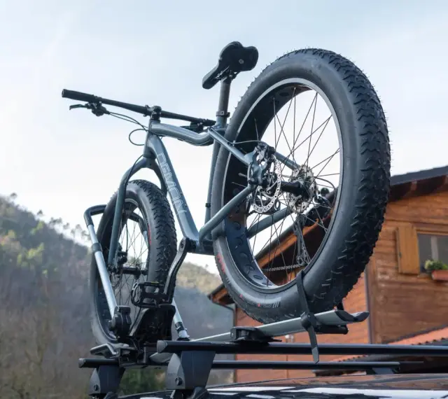 Gotowy montaż bagażnika rowerowego na dachu samochodu. Grube opony roweru fat bike są gotowe na przygodę.