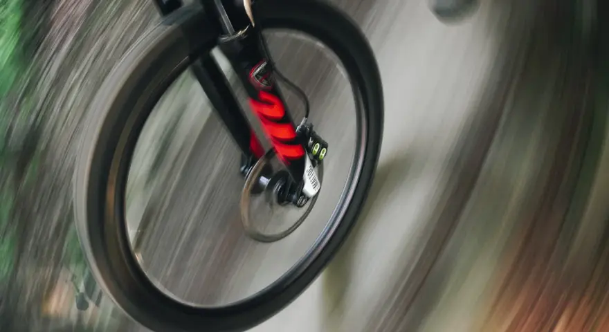 Przednie koło roweru enduro w ruchu, z widocznym amortyzatorem. Różne rodzaje amortyzatorów wpływają na jazdę.