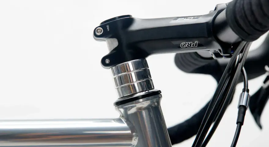 Czarne stery rowerowe PRO z aluminiowymi podkładkami, zamontowane na szarej ramie roweru szosowego.