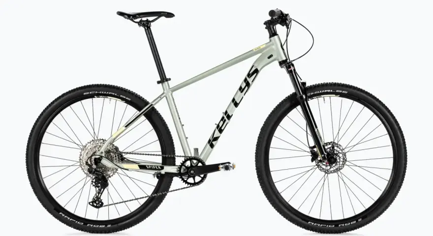 Szary rower Kellys Spider, rower bez amortyzatora, z czarnymi oponami Schwalbe i przerzutkami Shimano.