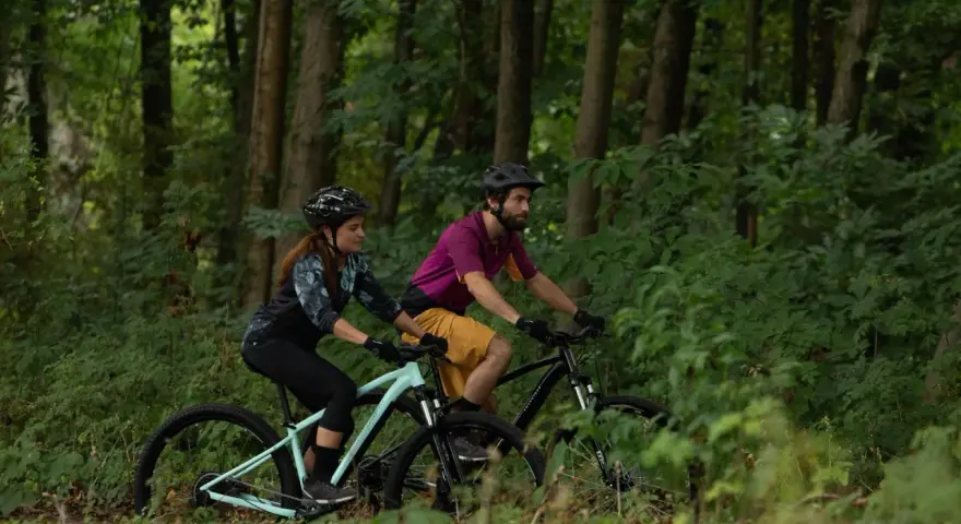 Para jadąca na rowerach MTB przez leśną ścieżkę. Czy to gravel czy mtb, jazda po lesie to czysta przyjemność.