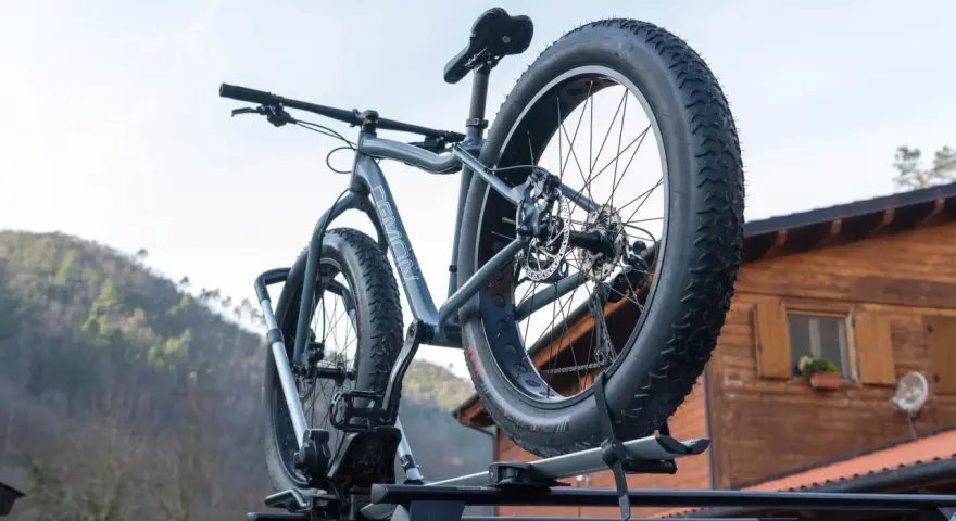 Gotowy montaż bagażnika rowerowego na dachu samochodu. Grube opony roweru fat bike są gotowe na przygodę.