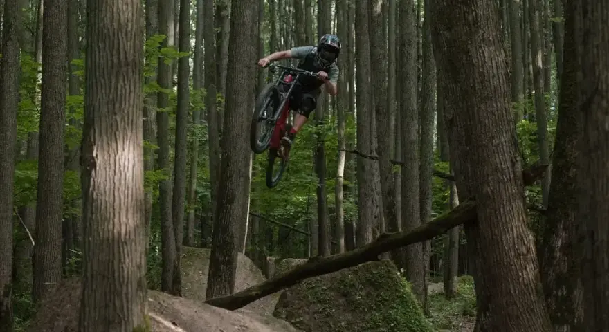 Kolarz MTB w powietrzu na leśnych trasach.