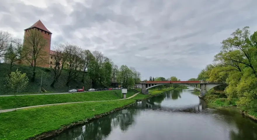 Oświęcim trasa: zamek, rzeka Soła i most na tle pochmurnego nieba.