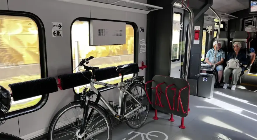 Wnętrze pociągu z miejscem na rowery. Widoczny stojak i uchwyty, jak powiesić rower w pociągu.