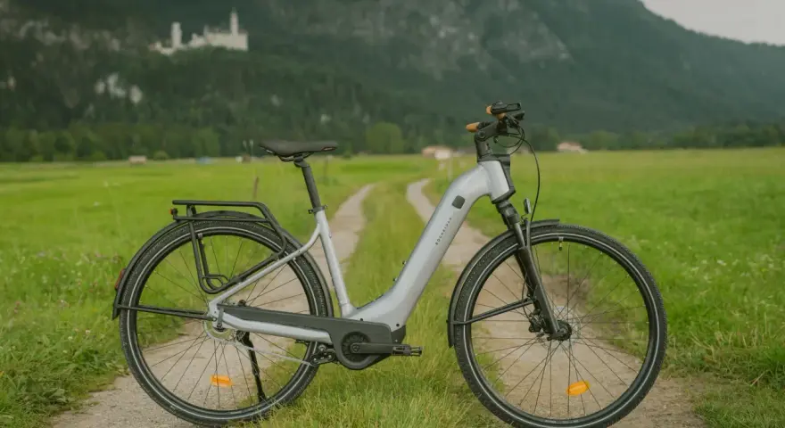Szary rower elektryczny na drodze polnej, z zamkiem na wzgórzu w tle. Idealny do zwiedzania, a jego znakowanie rowerów zapewni bezpieczeństwo.