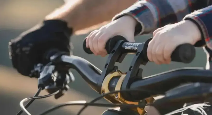 Dziecko trzyma kierownicę roweru, gotowe do jazdy. Wymiana manetek w rowerze to dobry pomysł na ulepszenie.