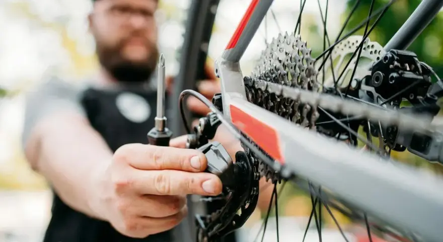 Mężczyzna z brodą dokręca śruby w rowerze, dbając o każdy szczegół.
