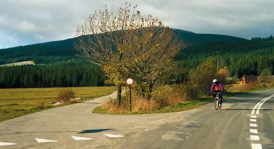 Rowerzysta mija znak drogowy, kierując się w stronę Babiej Góry.
