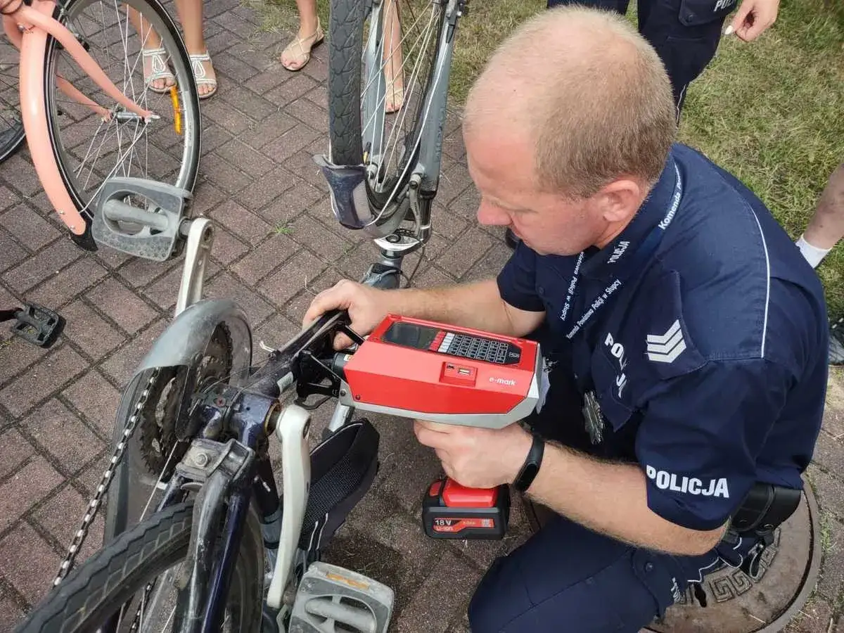 Policjant wykonuje czipowanie roweru za pomocą specjalnego urządzenia. Zabezpieczanie pojazdów przed kradzieżą.