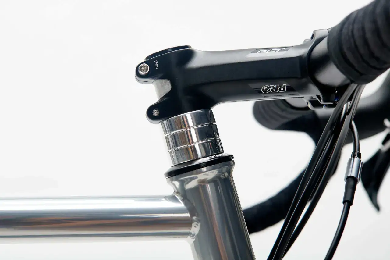 Czarne stery rowerowe PRO z aluminiowymi podkładkami, zamontowane na szarej ramie roweru.